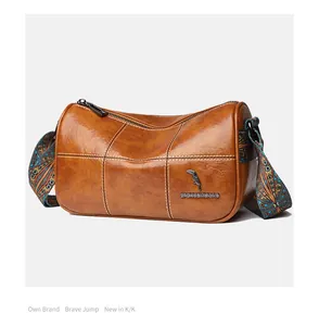 Detailed macro view of brown cylinder bag with metal bird logo and jacquard strap