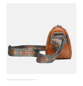 Detail of a brown leather cylinder bag featuring a colorful geometric woven strap