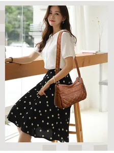 Detail van donkerbruine crossbodytas met meerdere ritscompartimenten en stikseldetails
