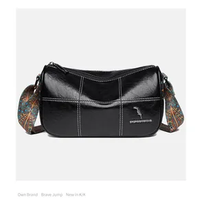 Detail of black wax leather barrel bag with contrast stitching and colorful wide strap
