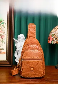 Close-up of retro brown PU leather chest bag with zipper pockets on wooden surface