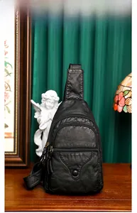 Detail of black pebbled PU leather chest bag with three zipper compartments and wide strap