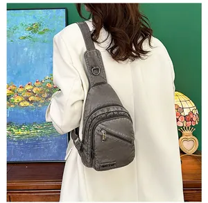 Détail du sac bandoulière gris en cuir plissé porté par un mannequin en veste blanche