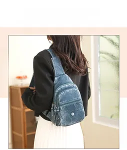 Detailed view of vintage blue washed crossbody bag with tassel and double zip pockets