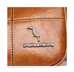 Macro detail of brown leather cylinder bag with cross stitching and metal woodpecker logo