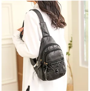 Detail of soft black leather chest bag with triple zip pockets and textured finish