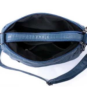 Blue washed leather crossbody bag featuring multi-compartment interior and metal zippers