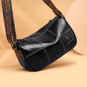 Black leather barrel bag with white stitching and colorful ethnic style shoulder strap