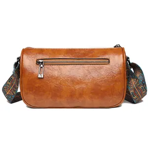 Brown leather barrel crossbody bag with bohemian patterned wide shoulder strap