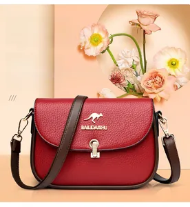 Detail of red pebbled leather saddle bag with gold kangaroo logo and metal clasp