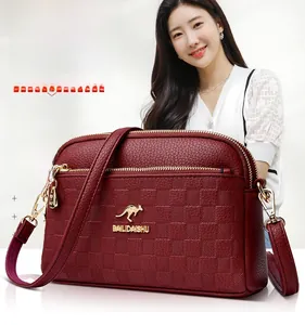 Detail view of burgundy leather crossbody bag with kangaroo logo and textured finish