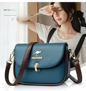 Detail of blue pebble grain leather handbag featuring golden kangaroo logo and brown trim