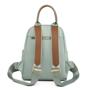 Mint green Oxford fabric backpack with brown leather trim shown from the back view