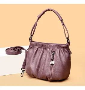 Detail of purple soft leather shoulder bag featuring side zipper and kangaroo pendant