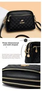 Detail of black pebbled leather crossbody bag with dual main compartments and gold hardware