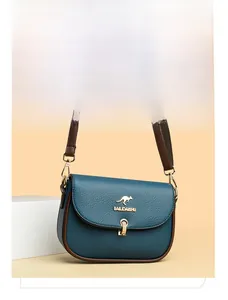 Detail of blue pebbled leather saddle bag with contrast brown strap and golden logo