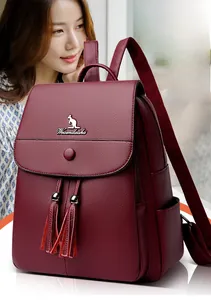 Detail of burgundy leather backpack with lychee texture and decorative tassels on model