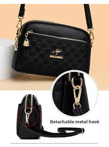 Detail view of black lychee leather crossbody bag with detachable golden hardware hooks