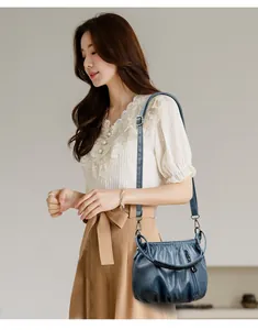 Blue soft leather shoulder bag with pleated texture and adjustable strap on model