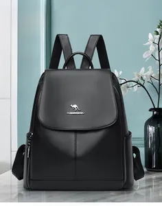 Detail of black pebbled leather backpack with gold kangaroo logo on a marble surface