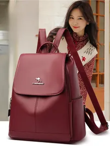 Close-up of wine red faux leather backpack showing pebbled texture and metal logo