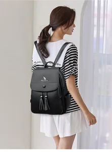 Detail of black pebbled leather backpack showing twin tassels and metal kangaroo logo