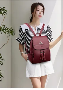 Close-up of red leather backpack featuring metal kangaroo logo and dual tassel accents