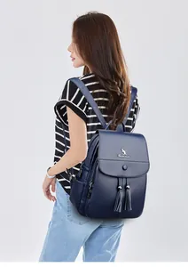 Detail of dark blue leather backpack featuring silver logo and decorative tassels