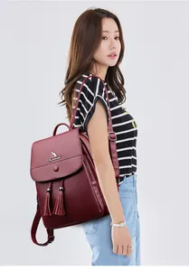 Detail of dark red leather backpack with gold kangaroo logo and decorative tassels