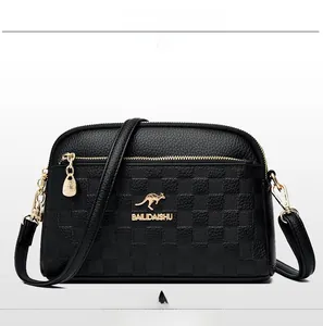 Detail of black pebbled leather crossbody bag with checkered texture and gold zippers