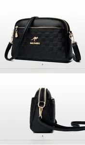 Detail view of black lychee grain leather crossbody bag with kangaroo logo and gold hardware