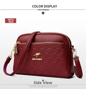 Detail of burgundy leather crossbody bag featuring three zippers and embossed texture