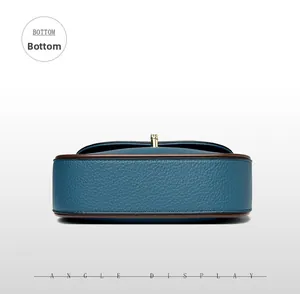 Detail view of the blue litchi grain leather bag bottom with brown trim and gold hardware
