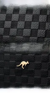 Detailed macro shot of black checkered leather texture with golden kangaroo logo