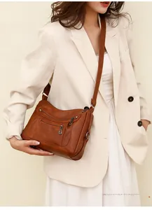 Close-up of brown vintage leather crossbody bag with multiple zippers worn by model