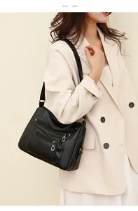 Detail of soft black leather shoulder bag with three silver zipper pockets on the front