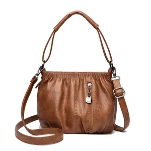 Brown soft leather bucket bag for women featuring top handles and adjustable strap