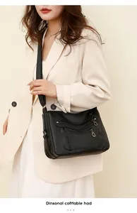 Detail view of a black multi-pocket crossbody bag in soft textured faux leather