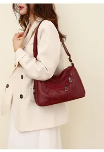 Detail of burgundy soft leather crossbody bag with multiple zippers and adjustable strap