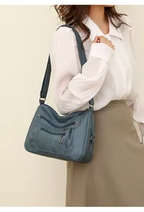 Detail of vintage blue PU leather crossbody bag with multi-zipper and metallic rivets