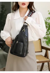 Detail der schwarzen Brusttasche mit gewebtem Riemen und goldenen Reißverschlussakzenten
