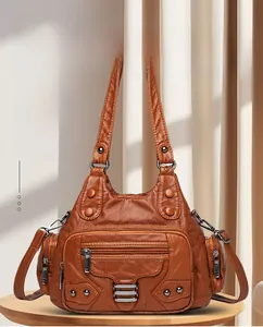 Détail d'un sac en cuir marron avec fermetures éclair, rivets et texture souple
