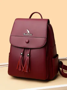 Women's burgundy leather backpack with lychee texture and tassel details in studio setting