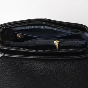 Internal view of black leather crossbody bag with multiple compartments and gold zipper