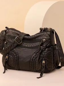 Black woven faux leather crossbody bag with multiple zippers and retro brass hardware