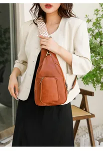 Nahaufnahme der braunen Vintage-Brusttasche aus Leder mit gewebtem geometrischem Gurt