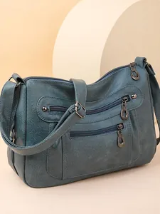 Minimalist soft faux leather crossbody bag in deep teal blue with multi-zipper pockets