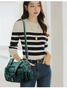 Détail d'un sac en cuir vert foncé avec poches zippées, rivets et poignée tissée