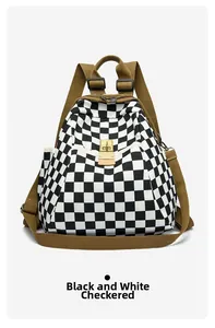 Détail d'un sac à dos à carreaux noirs et blancs avec fermoir doré et sangles marron