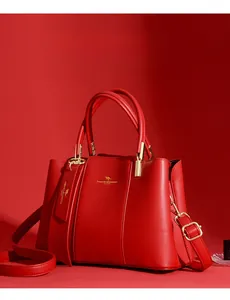 Detail view of red leather handbag with golden hardware and textured lychee pattern